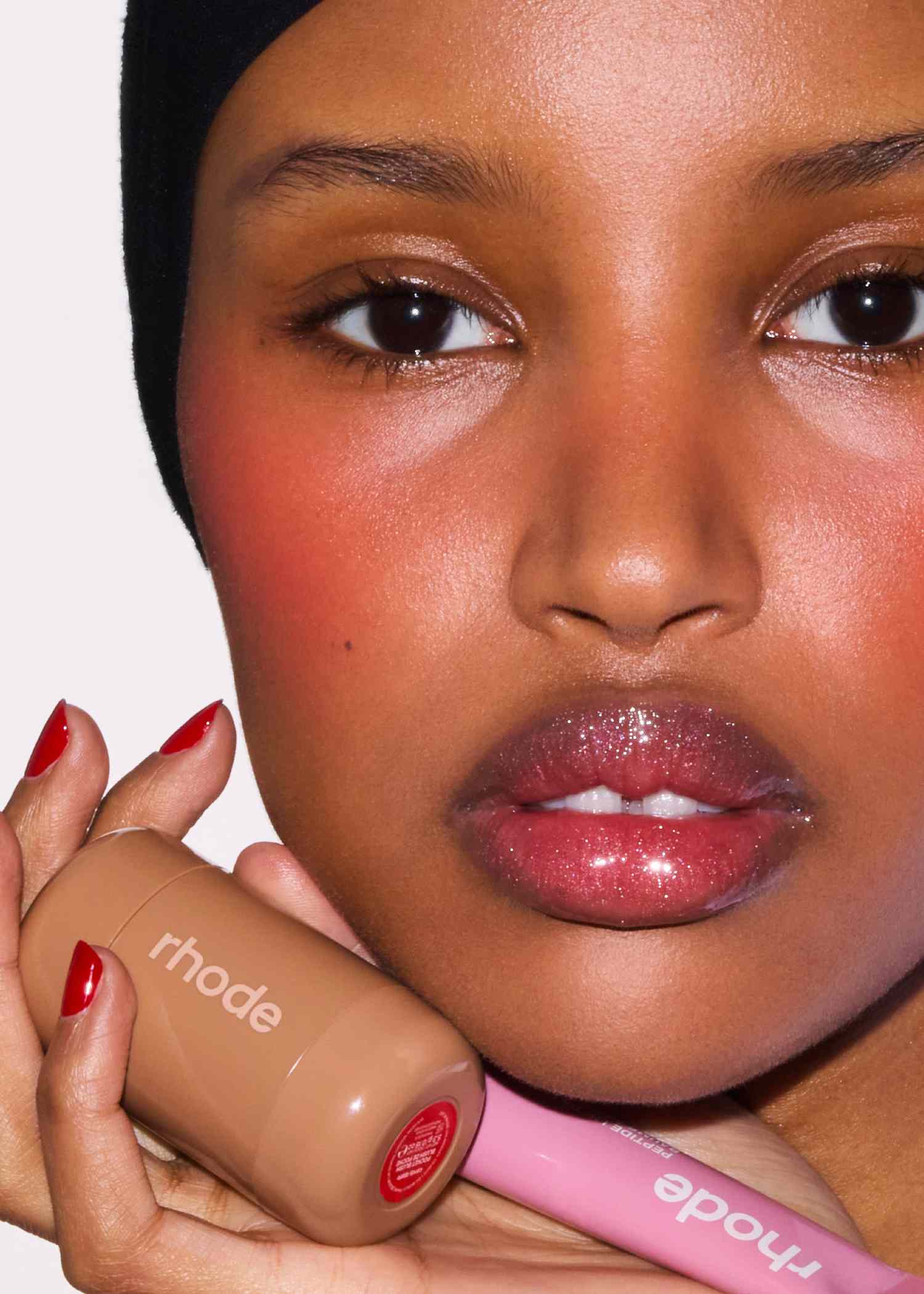 Macro close-up of a model's cheek featuring the warm, pearly red finish of Candy Apple Pocket Blush.