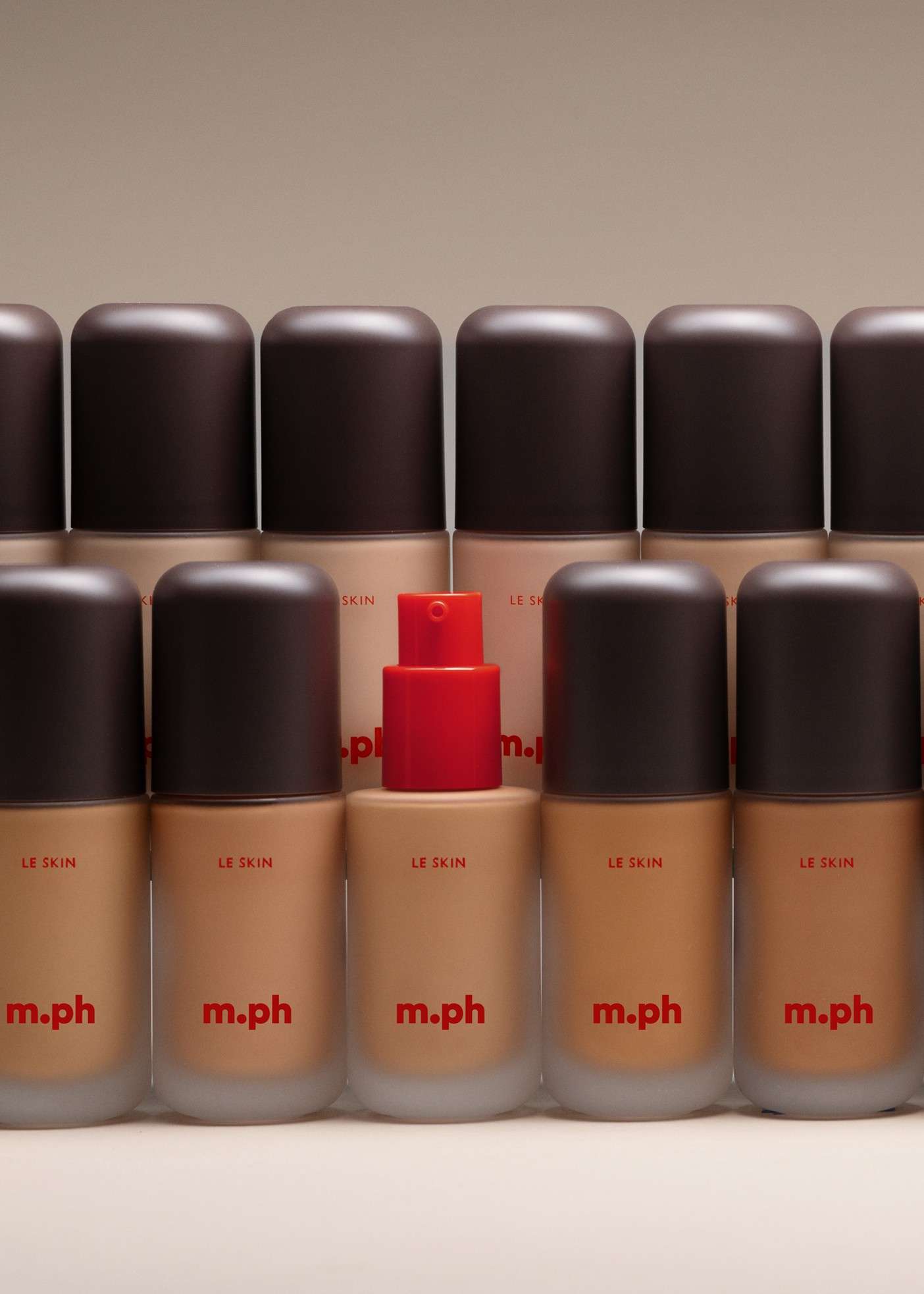 A lineup of several m.ph foundation bottles showing a range from fair to deep skin tones.