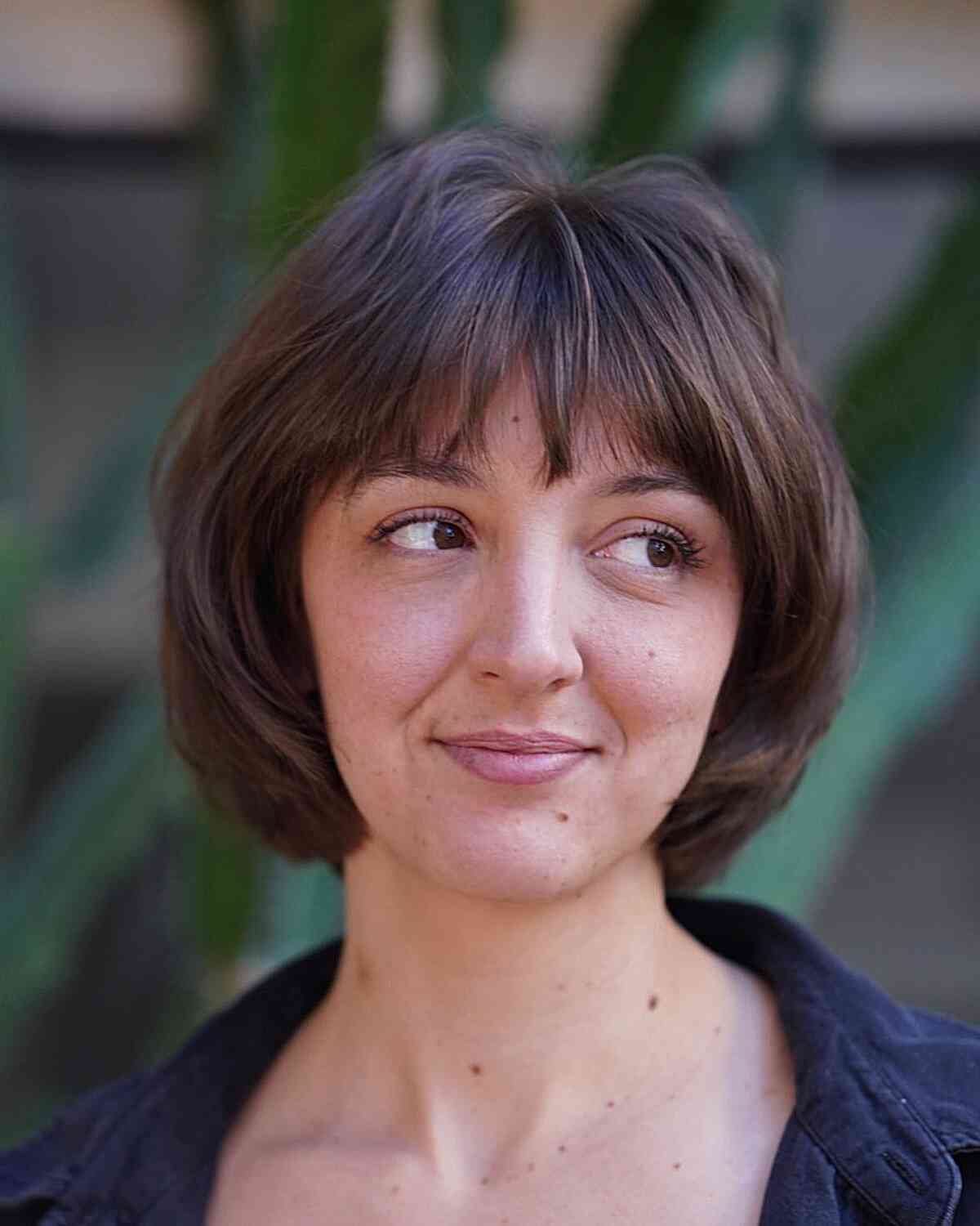A woman with a rounded bob cut featuring soft bangs and internal layers.