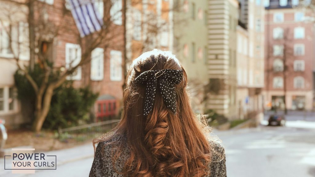 The back of a woman's head featuring a large, soft fabric hair bow accessory.