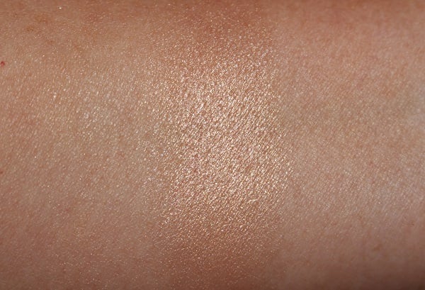 Swatch demonstrating the finish of powder highlighter layered with balm on top.