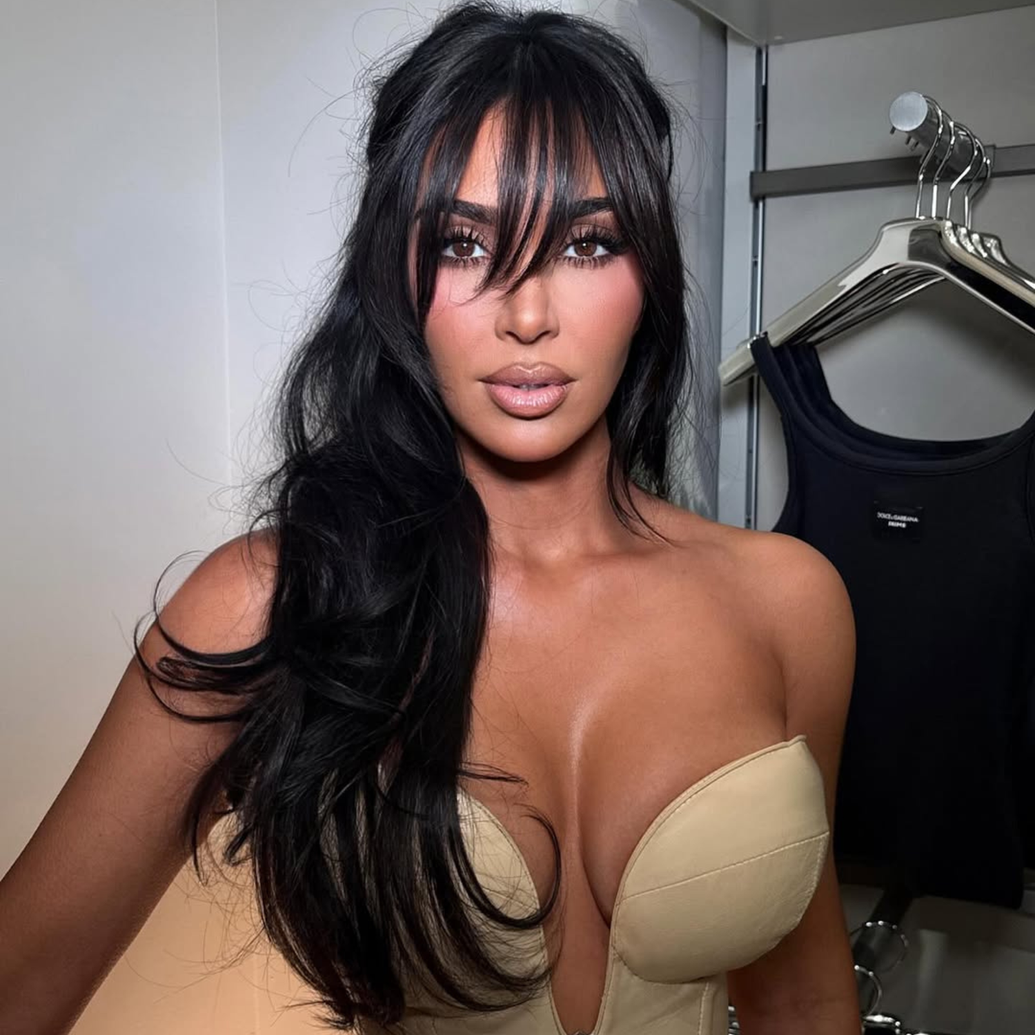 Kim Kardashian with long, soft curtain bangs and a voluminous blowout.