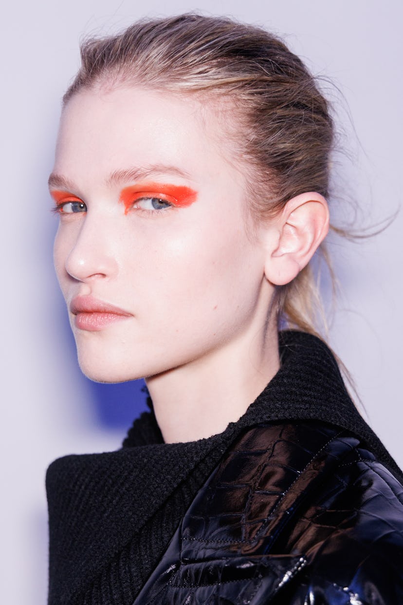 Close-up of a model from the Sportmax Fall/Winter 2026 show with bold orange eye makeup.