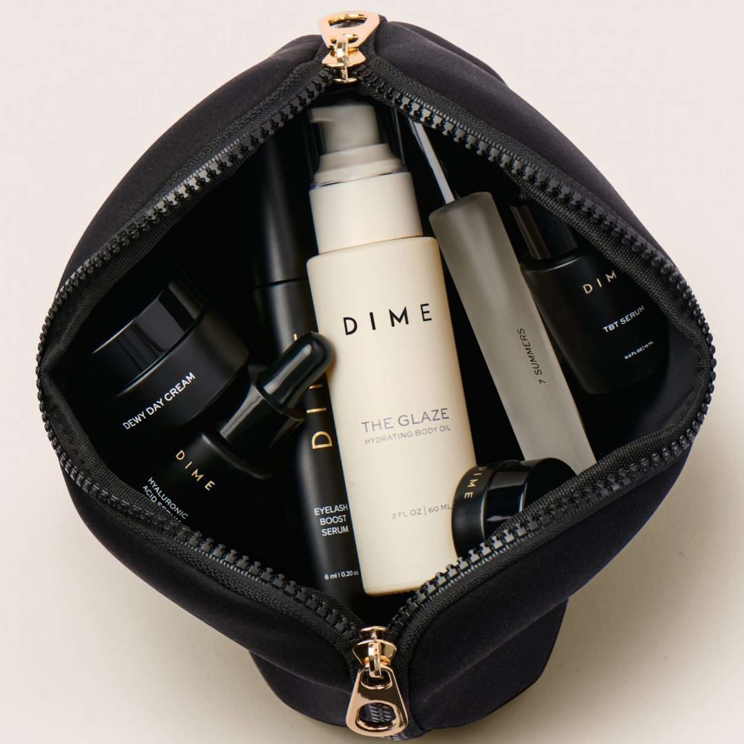 An open black makeup bag filled with various Dime Beauty skincare products.